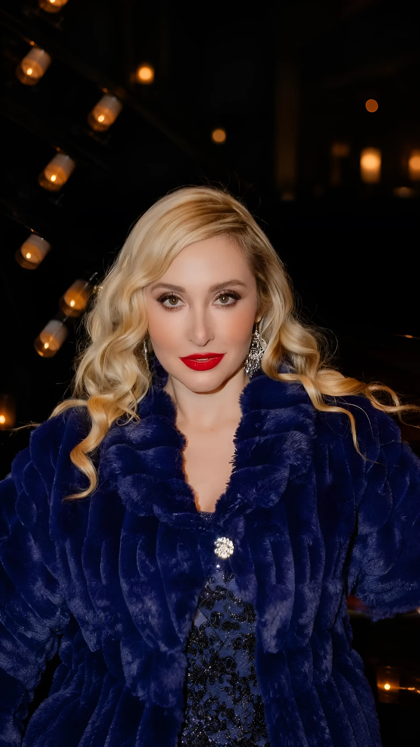 Venicia Rasmussen, opera soprano, in a navy fur stole and red lipstick before warm stage lamps