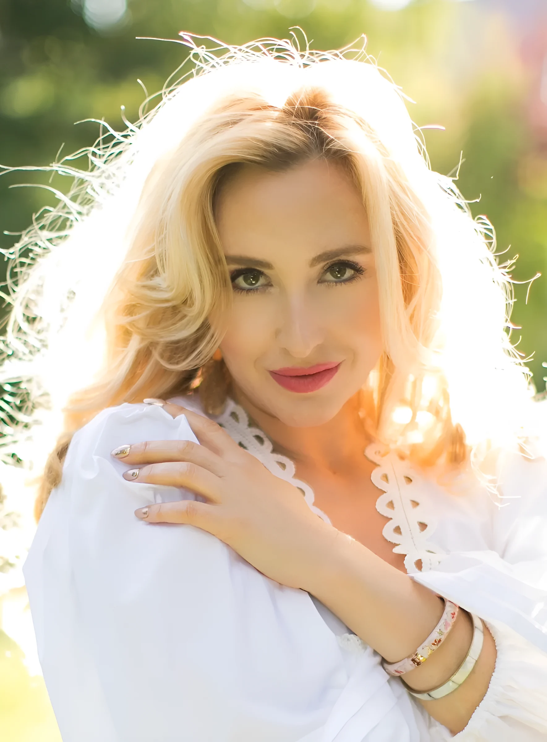 Venicia Rasmussen, soprano, backlit in a summer garden in a white lace blouse